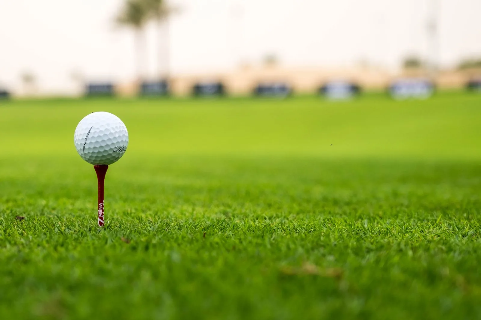 Bóng golf đặt trên tee đỏ giữa sân cỏ