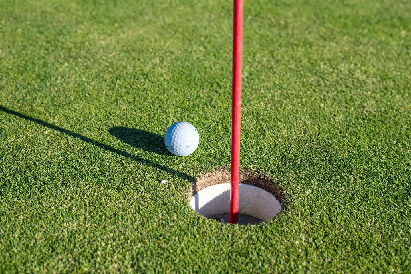 Bóng golf nằm sát lỗ cạnh cán cờ đỏ